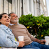 Hispani senior couple sitting outside on a bench and drinking coffee