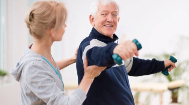 A senior male lifting dumbbells with a female personal trainer.