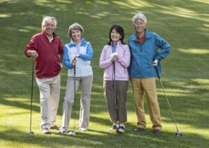 Two couples of seniors on a golf course ready to play.