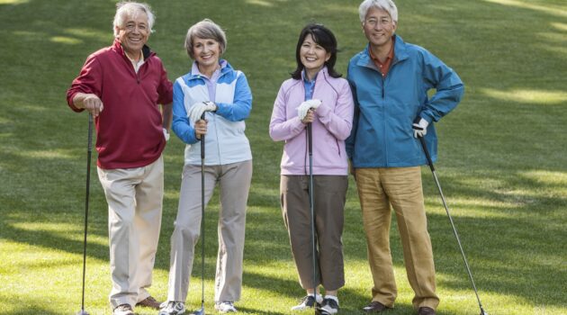 Two couples of seniors on a golf course ready to play.